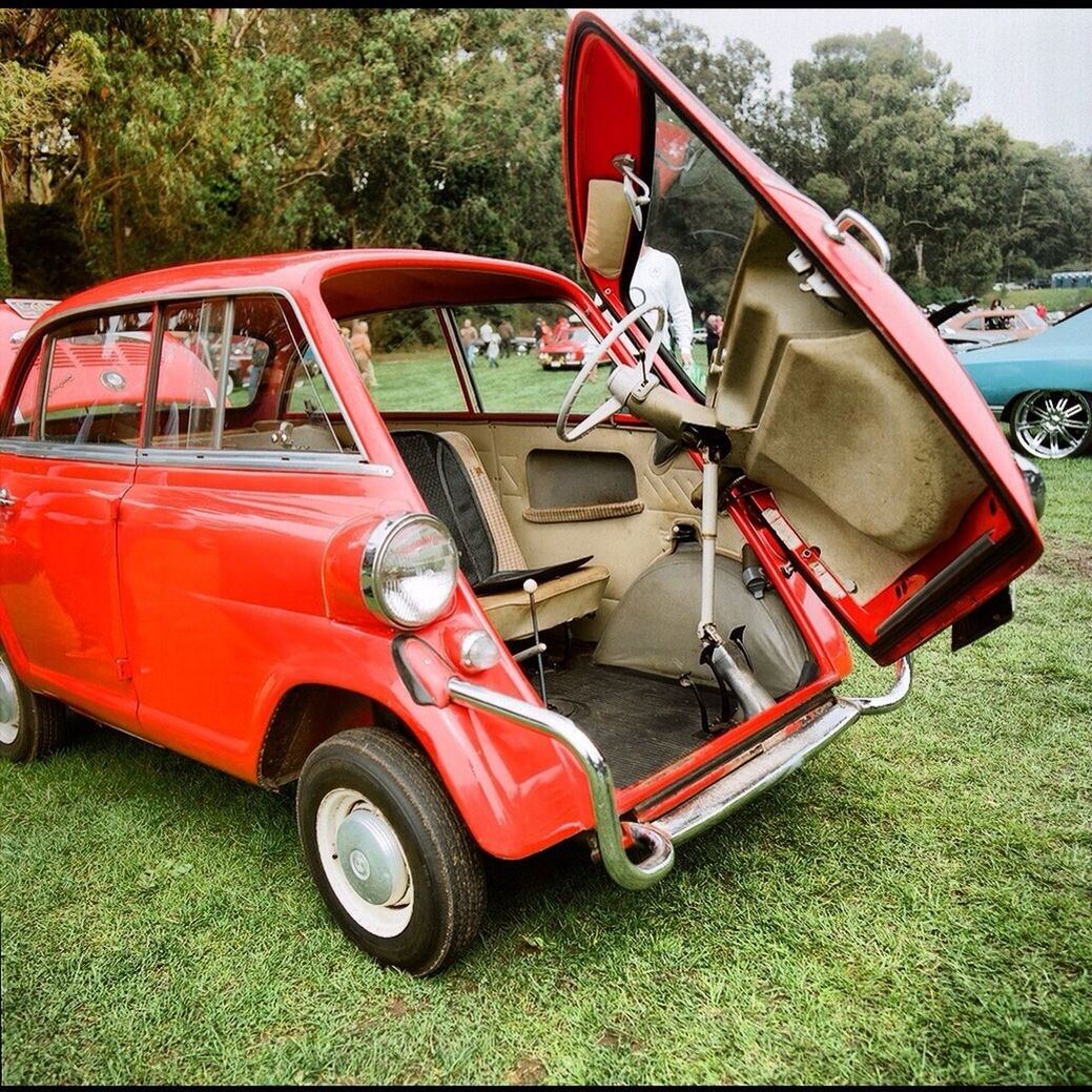 transportation, mode of transport, land vehicle, car, grass, red, stationary, field, vintage car, nautical vessel, day, travel, wheel, boat, outdoors, no people, tire, sunlight, close-up, parking