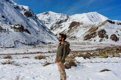 Side view of man standing by snowcapped mountains 