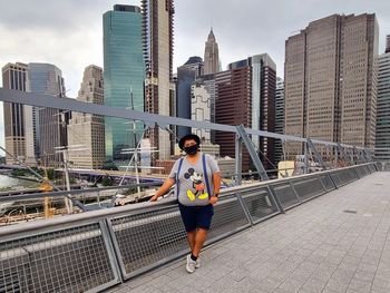 Full length of man standing by railing against buildings in city