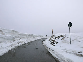 Road amidst snow covered land against clear sky