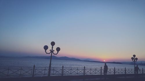 Pier on sea against clear sky at sunset