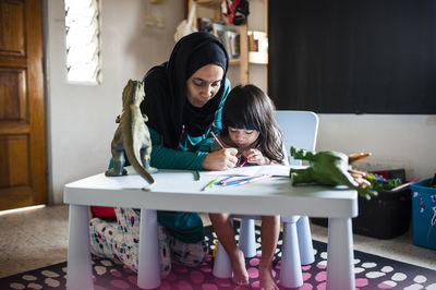 Woman assisting son in drawing at home