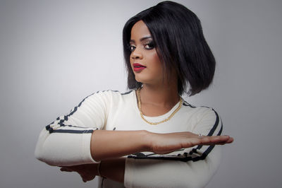 Fashionable woman with arms crossed against white background