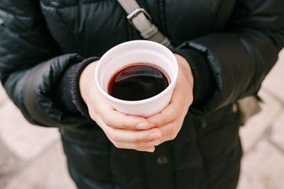 Midsection of man holding coffee cup