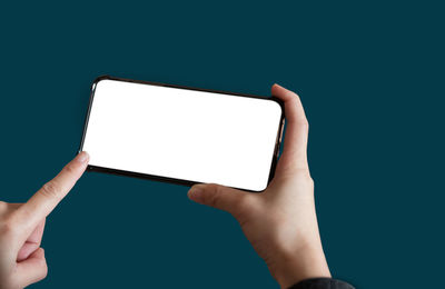 Cropped hands of woman holding digital tablet against blue background