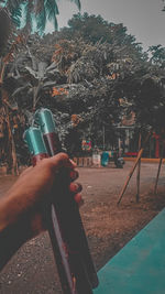 Midsection of man holding cigarette on tree