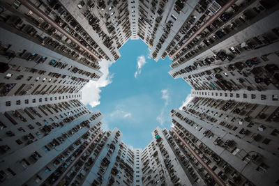 Directly below shot of buildings against cloudy sky