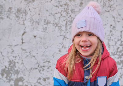 Portrait of smiling young woman standing against wall