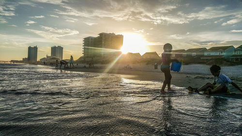 People on water against sky during sunset