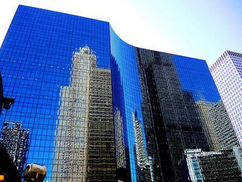 Low angle view of skyscrapers against blue sky