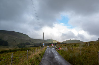 Road amidst field against sky