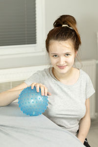 Portrait of cute girl sitting on bed at home