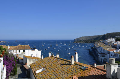 Houses by sea against clear blue sky