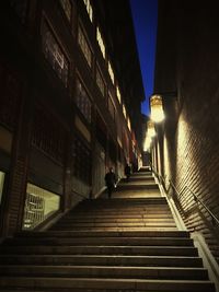 Low angle view of illuminated steps amidst buildings at night