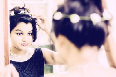 Woman wearing tiara while looking herself in mirror