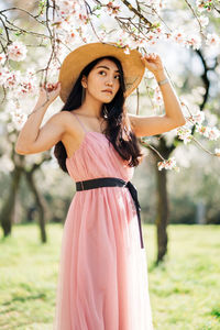 Young woman standing against pink flowers