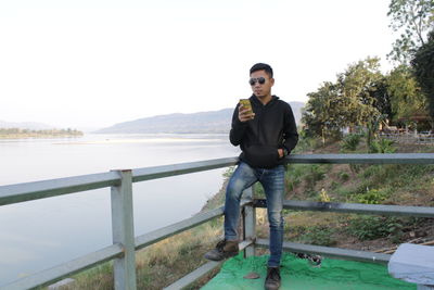 Portrait of young man standing by railing