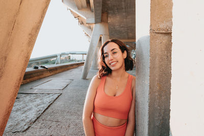 Portrait of young woman standing against wall