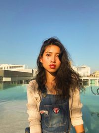 Portrait of young woman standing against clear sky