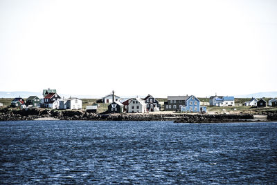 Sea by houses against clear sky