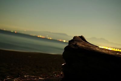 Close-up of beach against sky during sunset