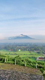 Scenic view of field and mount merapi against sky. mount merapi is one of most active volcano.