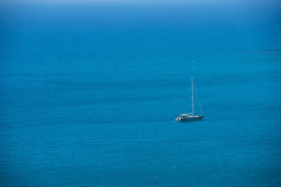 Sailboat sailing in sea against blue sky