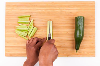 High angle view of hand holding vegetables on cutting board