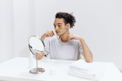 Portrait of young woman drinking water against white background