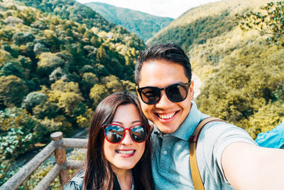 High angle portrait of smiling friends wearing sunglasses against mountains