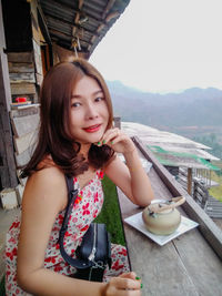 Portrait of happy woman holding drink on table
