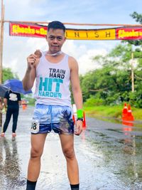 Portrait of athlete holding medal while standing on wet street