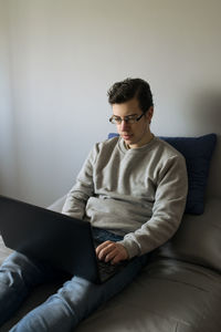 Young woman using laptop while sitting on sofa at home