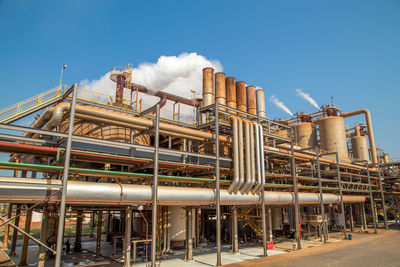 Low angle view of industry against blue sky