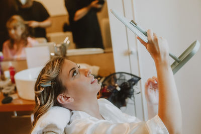 Young woman holding mirror at spa