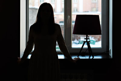 Rear view of woman photographing through window at home