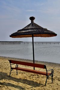 Bank and parasol on beach of lake against sky