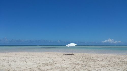 Scenic view of beach against clear blue sky