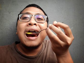 Close-up portrait of man wearing eyeglasses against wall