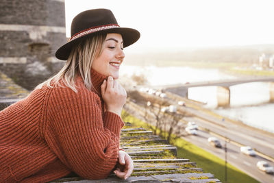 Portrait of smiling young woman in hat against sky