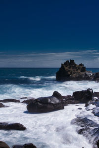 Scenic view of rocks on beach against sky