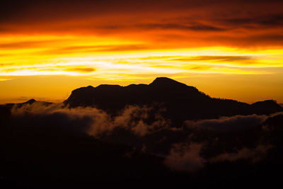 Scenic view of silhouette mountains against orange sky