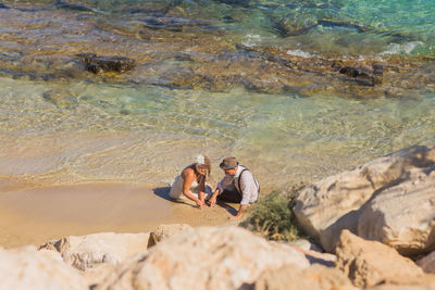 Men on rock at sea shore