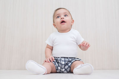 Cute boy looking away while sitting on floor