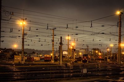 Illuminated railroad tracks against sky at night