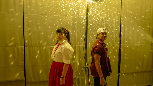 Man and woman standing by curtain with disco ball reflection