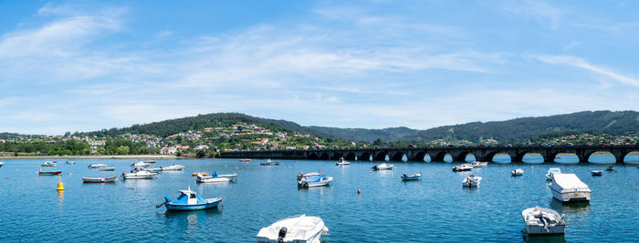 Panoramic view of boats moored at sea against sky