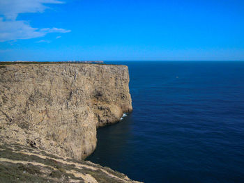 Rock formations by sea against blue sky