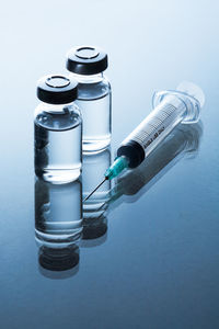 Close-up of vial and syringe on blue background