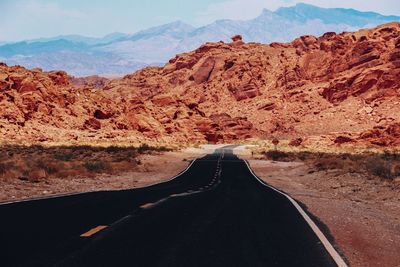 Road on arid landscape against rocky mountains